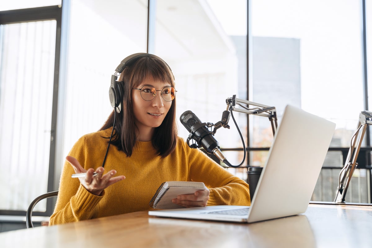 Female podcaster recording audio podcast in studio